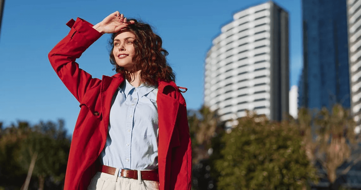 Woman in a red coat looking toward a city skyline