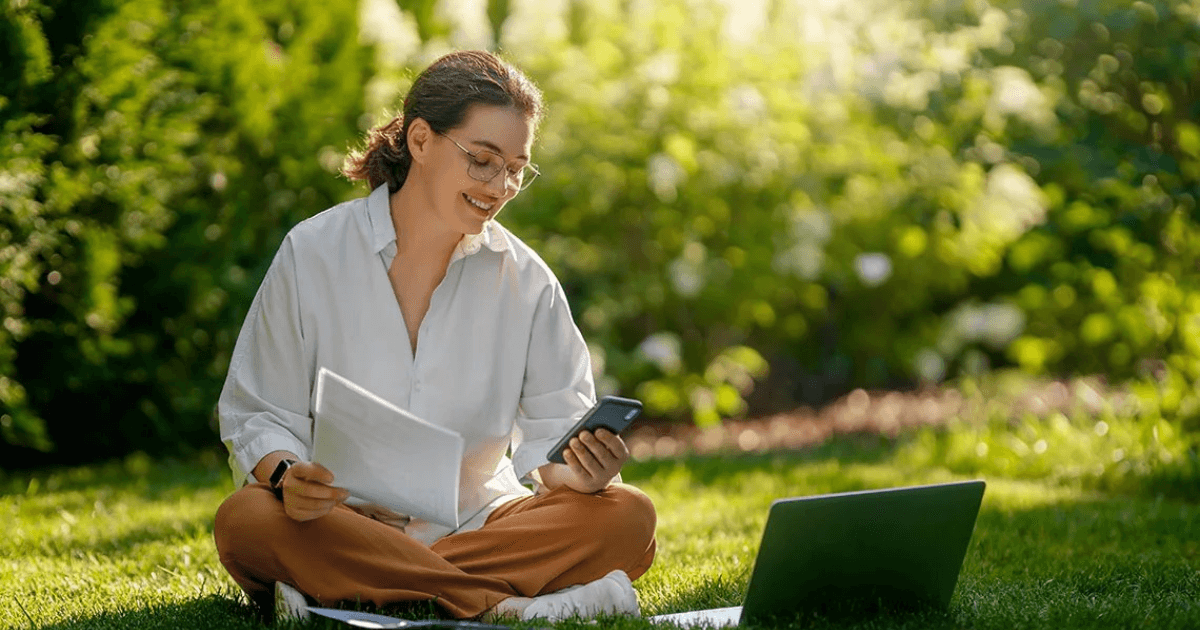 Woman reviewing paperwork and her phone outdoors