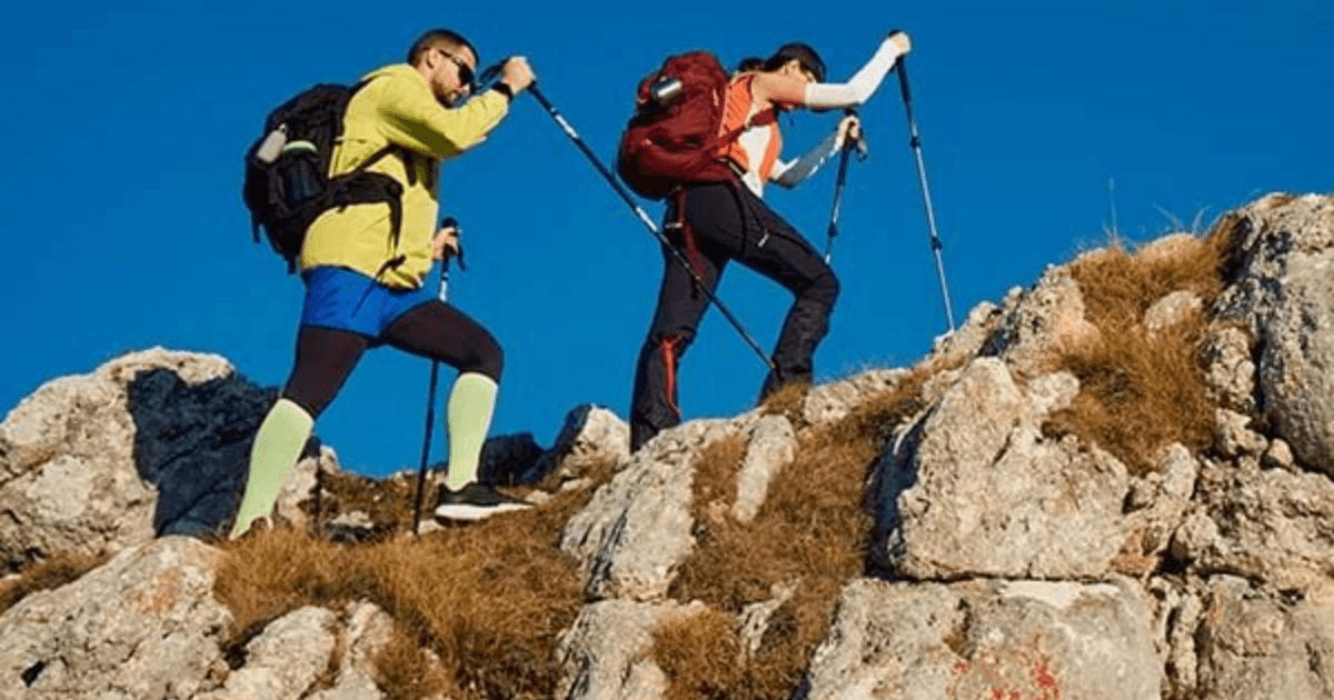 Two hikers climbing toward a mountain summit