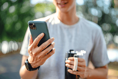 Person checking financial information on a smartphone while holding a travel mug