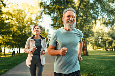 Older couple jogging together in a sunny park