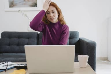 Stressed woman at desk reviewing finances after missing a credit card payment