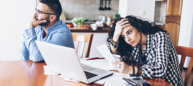 Distressed couple looking at bills at kitchen table