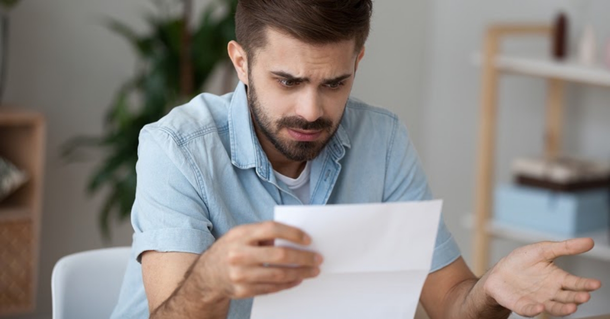 Man looking at credit card statement with worried expression