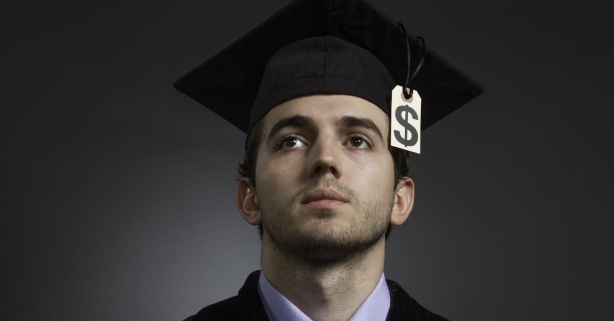 Man wearing graduation cap with a dollar sign hanging from it